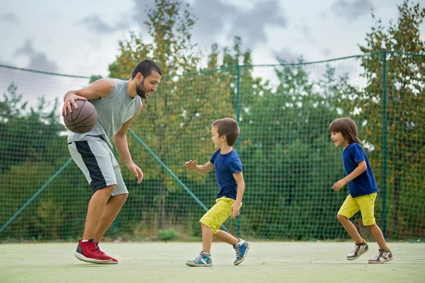 Jonge kinderen, broers en hun vader, spelen basketbal — Stockfoto