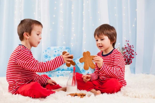 Dos niños felices comiendo galletas en Navidad y bebiendo leche —  Fotos de Stock