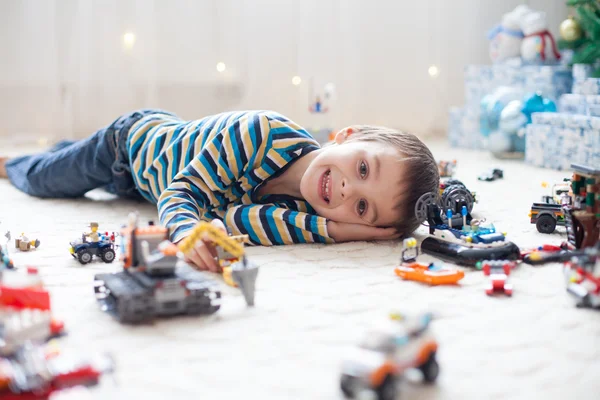 Pequeño niño jugando con un montón de juguetes de plástico de colores en interiores —  Fotos de Stock