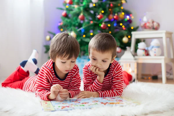 Dos chicos, leyendo un libro delante del árbol de Navidad — Foto de Stock