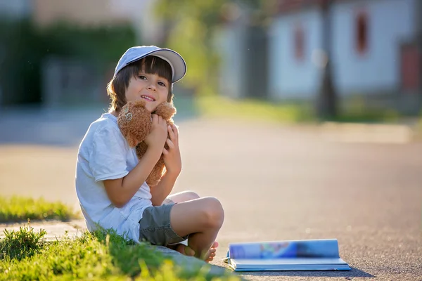 Hermoso niño, leyendo un libro en la calle, sentado wi — Foto de Stock