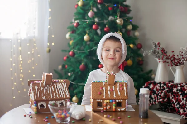 Niedlicher kleiner Junge, der Lebkuchenhaus für Weihnachten backt — Stockfoto