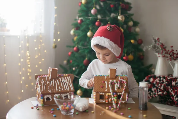 Niedlicher kleiner Junge, der Lebkuchenhaus für Weihnachten backt — Stockfoto
