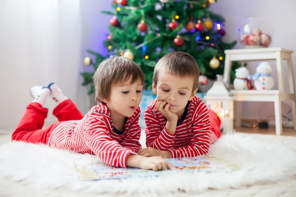 Dos chicos, leyendo un libro delante del árbol de Navidad — Foto de Stock