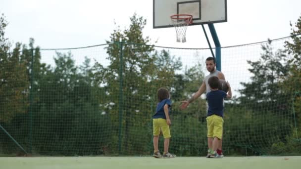 Маленькие дети, братья и их отец, играют в баскетбол — стоковое видео