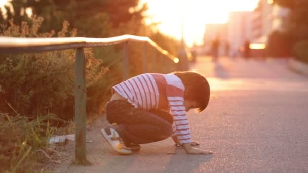 Carino bambino in età prescolare, giocando con i giocattoli per strada al tramonto, ora di autunno — Video Stock