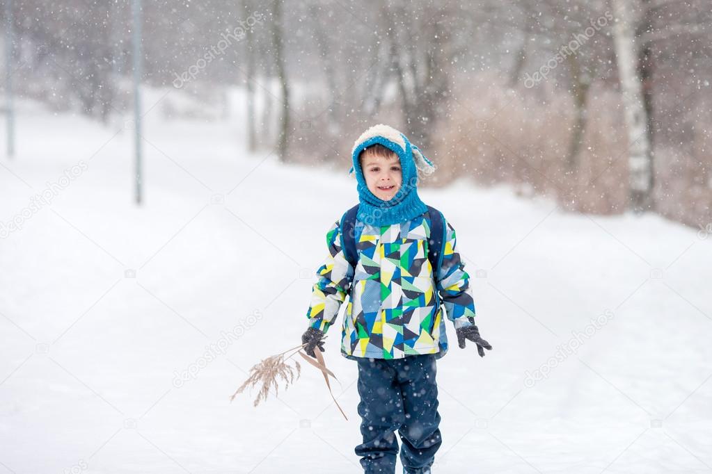 Cute little boy with backpack, going on a ski holiday, walking i