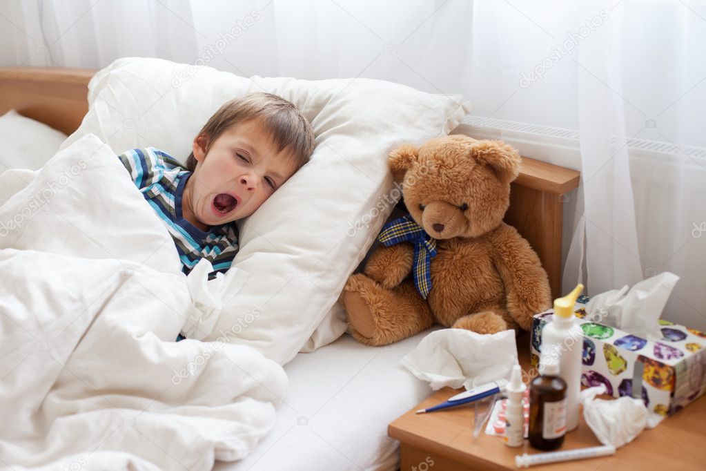 Sick child boy lying in bed with a fever, resting