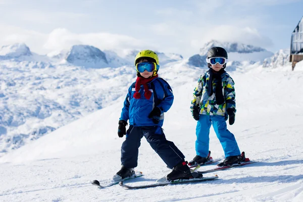 Двое маленьких детей, братья и сестры, катание на лыжах в австрийской горе — стоковое фото