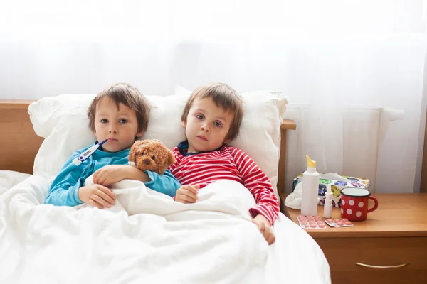 Dois meninos doentes, irmãos, deitados na cama com febre — Fotografia de Stock