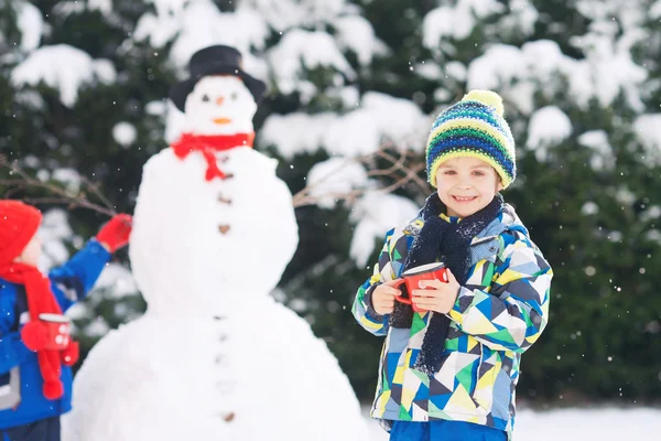 Felice bella bambini, fratelli, costruzione pupazzo di neve in giardino a — Foto Stock