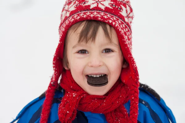 Γλυκό μικρό παιδί, αγόρι, τρώγοντας μπισκότο στο χιόνι χειμώνα ώρα — Φωτογραφία Αρχείου
