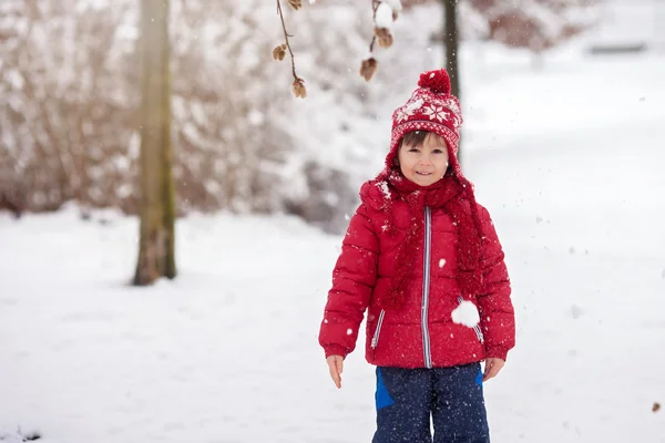 Sevimli küçük çocuk, bahçede karda oynuyor — Stok fotoğraf