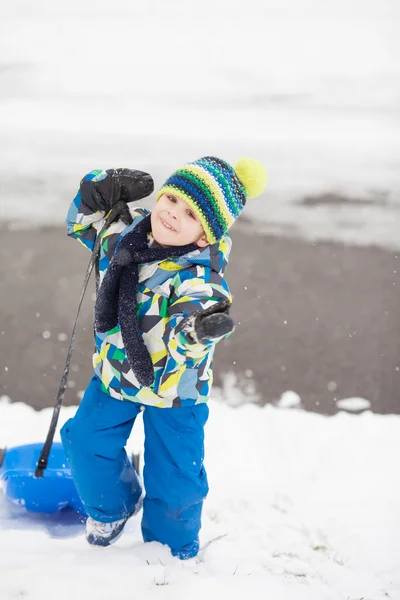 Sladký chlapeček, který se v zimě na sníh sáže, baví — Stock fotografie