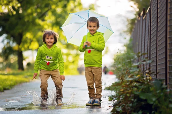 Two adorable little boys, playing in a park on a rainy day, play — Stock Photo, Image