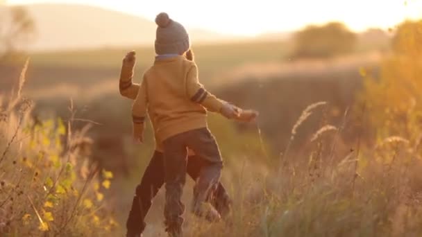 Dos niños adorables, divirtiéndose al atardecer, haciendo caras graciosas y bailando en un pequeño sendero rural — Vídeos de Stock