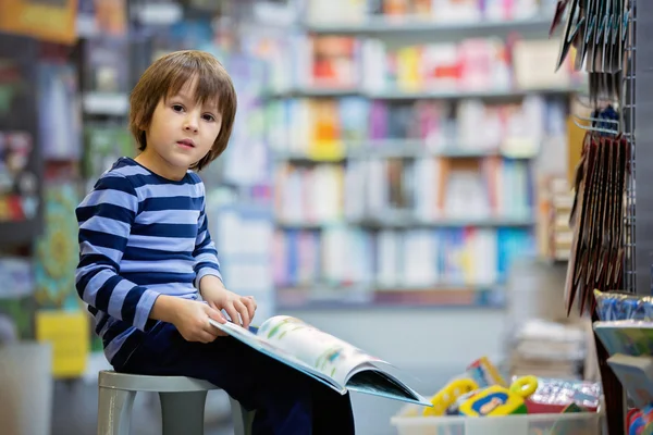 Criança adorável, rapaz, sentado numa livraria — Fotografia de Stock