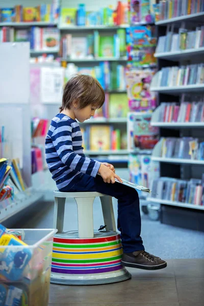 Очаровательный маленький ребенок, мальчик, сидит в книжном магазине — стоковое фото