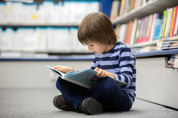 Bir kitapçıda oturan sevimli küçük çocuk, çocuk, — Stok fotoğraf