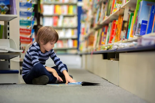 Adorable petit enfant, garçon, assis dans une librairie — Photo