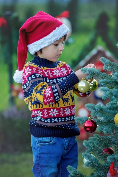 Schattige kleine jongen, versieren kerstboom, buiten — Stockfoto