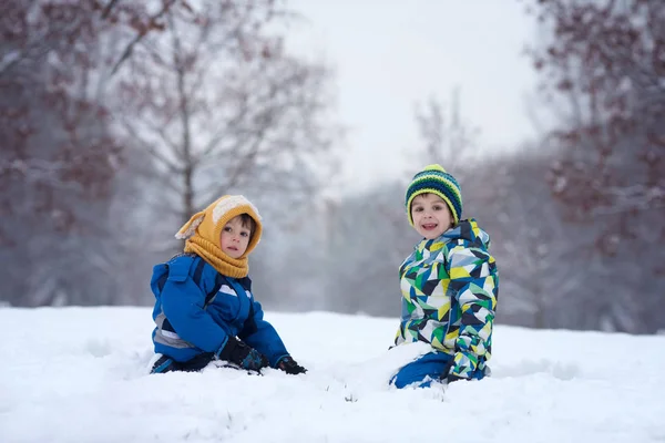 Två pojkar, bröder, spelar i snön med snöbollar — Stockfoto