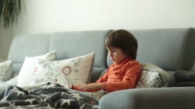 Bir koltukta oturan bir dergi okuma ufaklık, yumuşak battaniye ile örtülü