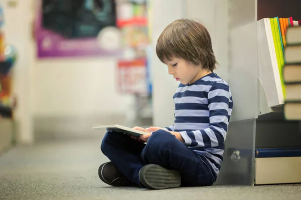 Schattig kindje, jongen, zittend in een boekhandel — Stockfoto