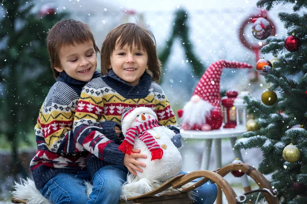 Dos niños, hermanos, sentados en un trineo junto a un cristo — Foto de Stock