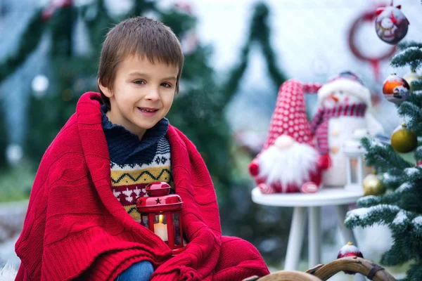Niedliches kleines Kind, Junge, auf einem Schlitten neben einem Weihnachtsbaum sitzend — Stockfoto