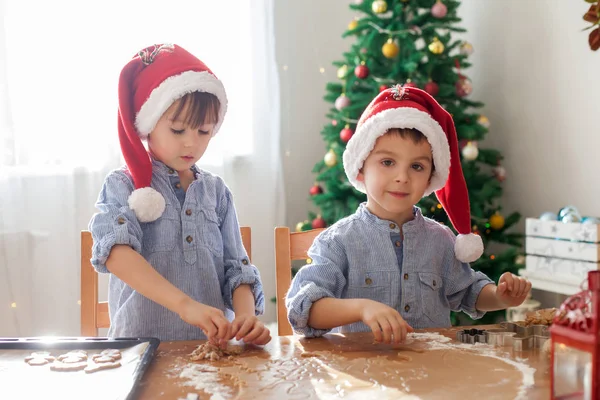 Dos chicos lindos con sombrero de santa, preparando galletas en casa, Christm — Foto de Stock
