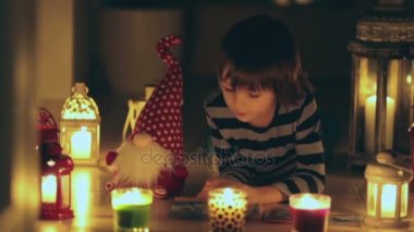 Güzel çocuk dergisi yere uzanarak okuma, onun etrafında mumlar
