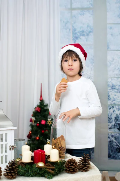 Рождественский портрет милого маленького дошкольника, поедающего печенье — стоковое фото