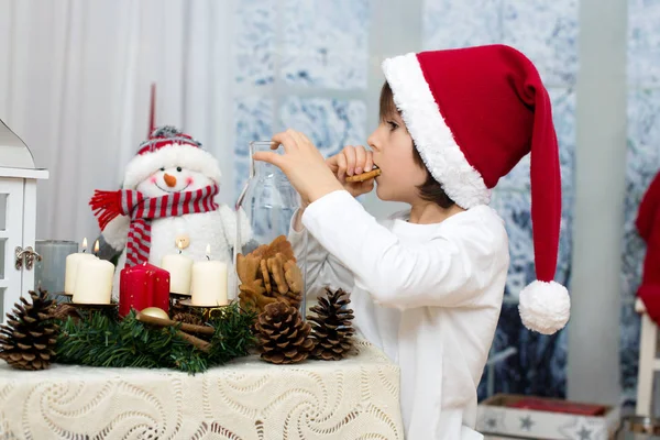 Christmas portrait of cute little preschool boy, eating cookies — Stock Photo, Image