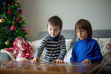 Two sweet children, collect puzzles at home on Christmas clipart