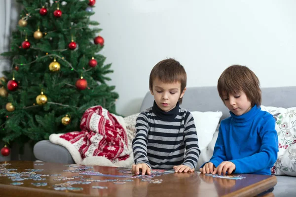 Двое милых детей, собирают головоломки дома на Рождество — стоковое фото