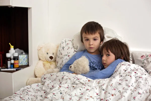 Zwei niedliche kranke Kinder, Jungen, die mit Fieber im Bett liegen — Stockfoto