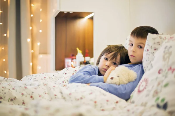 Двоє милих хворих дітей, хлопчиків, які перебувають у ліжку з гарячкою — стокове фото