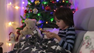 Sevimli okul çocuğu, çikolata yeme ve yılbaşında evde kitap okurken