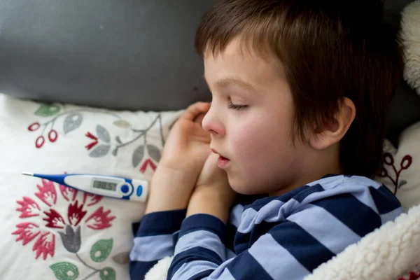 Bambino malato, ragazzo, con la febbre alta che dorme sul divano a — Foto Stock