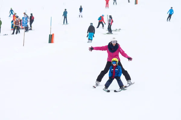 Söt ung pojke och hans mor, lära sig att åka skidor på en mild ski sl — Stockfoto