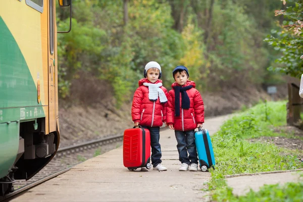 两个男孩在火车站等候火车与 suitca — 图库照片
