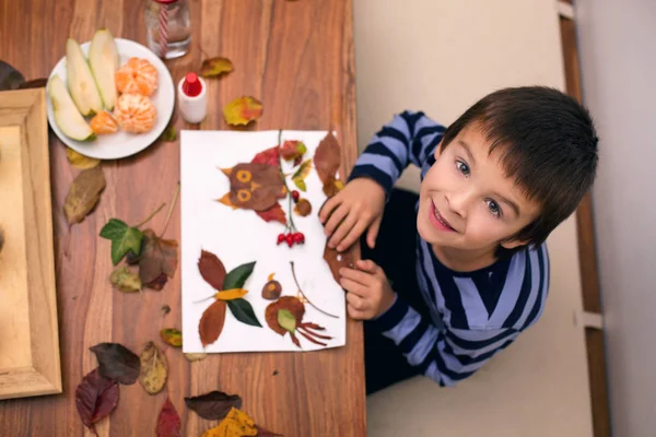 Tatlı çocuk, çocuk sanat tutkal kullanarak yaprakları uygulayarak, bir — Stok fotoğraf