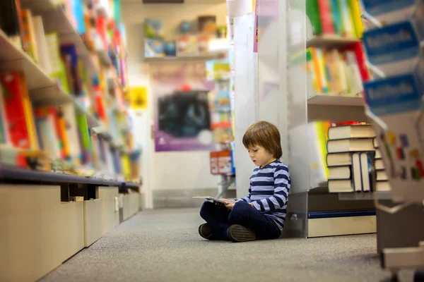 Adorable little child, boy, sitting in a book store — Stock Photo, Image