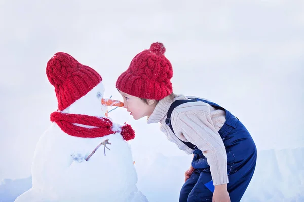 幸せな美しい子鼻 t、冬の庭で雪だるまを構築 — ストック写真