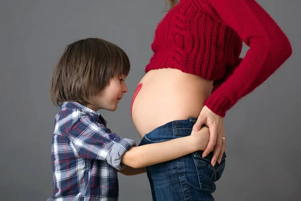 Piękne dziecko przedszkola, przytulanie jego mama w ciąży — Zdjęcie stockowe