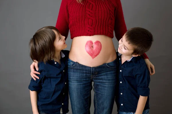 De beaux enfants d'âge préscolaire, embrassant leur mère enceinte — Photo