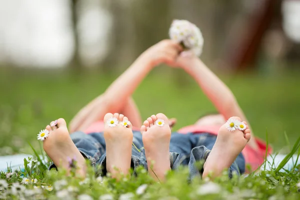 Petits enfants heureux, couchés dans l'herbe, pieds nus, marguerites aro — Photo