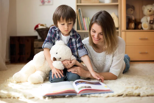 Junge Mutter, las ihrem Kind ein Buch vor, Junge im Wohnzimmer — Stockfoto