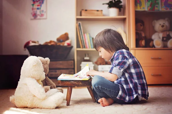Aranyos kis gyerek, iskoláskor előtti fiú egy könyvet a teddy kell — Stock Fotó